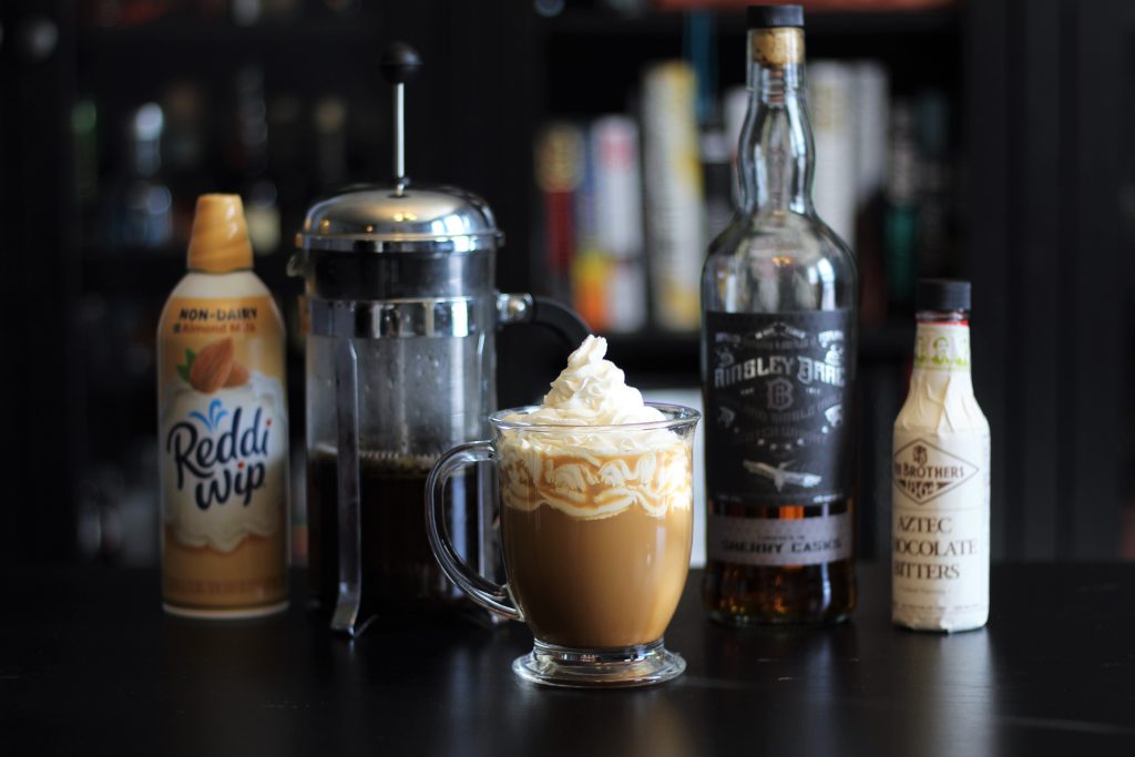 Corellian Coffee in a clear mug with whipped cream. ingredients in background 