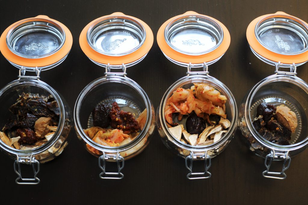 The four glass jars with various vegetables and jerky added.