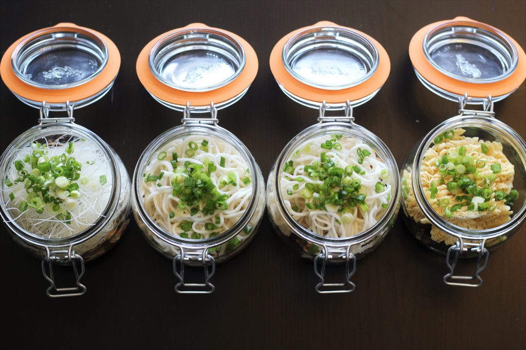 The four glass jars with various noodles added.