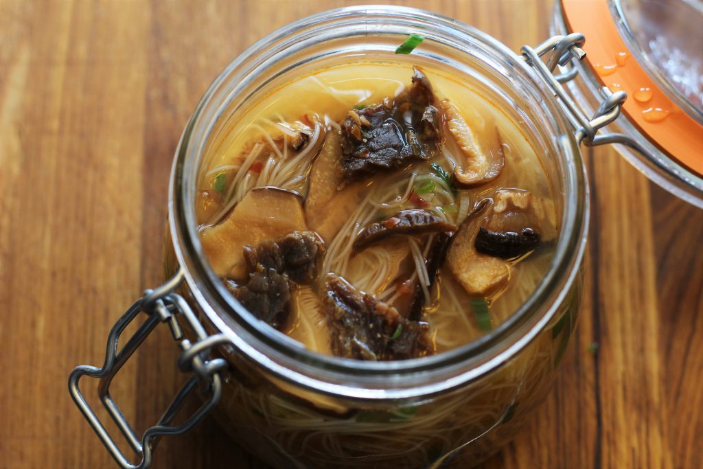 A close up of the prepared noodle jar with noodles, jerky, and shiitakes.