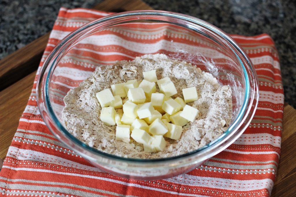 Cubed butter adding to the mixing bowl of dry ingredients. 