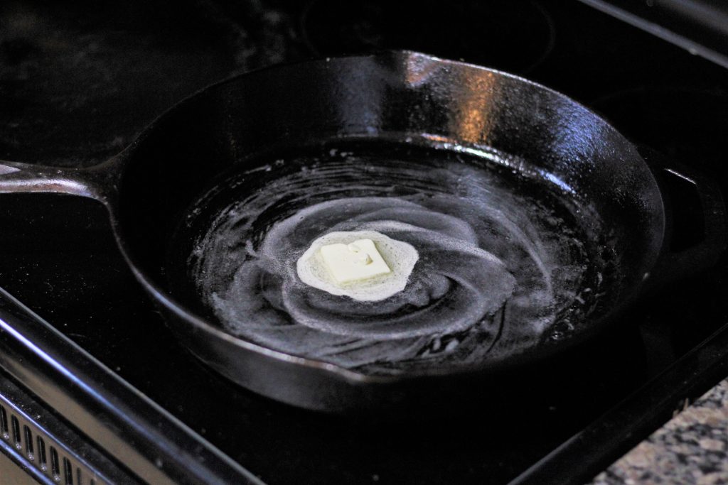 A pat of butter melting in a cast iron pan. 