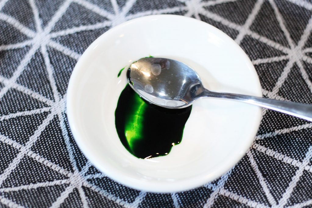 A small ceramic bowl with mixed food coloring and tiny spoon. 