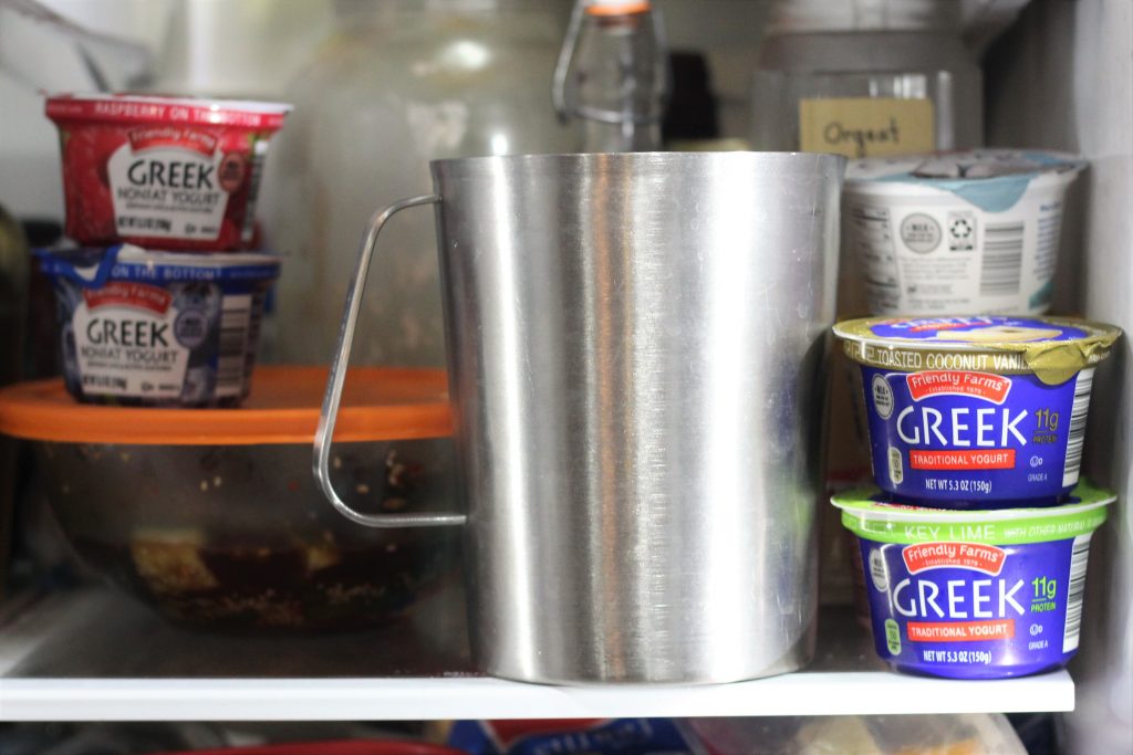 The metal pitcher on a shelf in a fridge. 