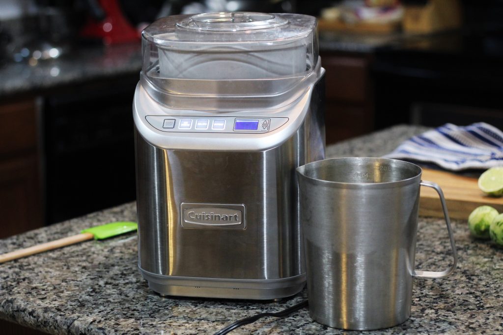 A Cuisinart ice cream machine on a counter with the metal pitcher beside it. 