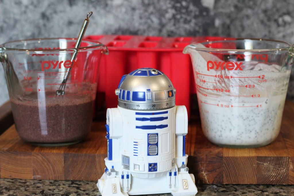 Foreground: R2-D2 kitchen timer.
Middleground: measuring cup with acai coconut milk, measuring cup with coconut milk
Background: silicone popsicle mold