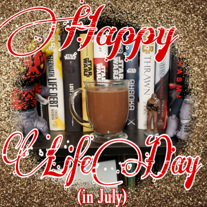 A stylized image with a photo of mug of hot chocolate in the center. A glitter border surrounds it. Over layed is a large, fancy script saying "Happy Life Day", underneath is smaller, standard text saying "(in July)"